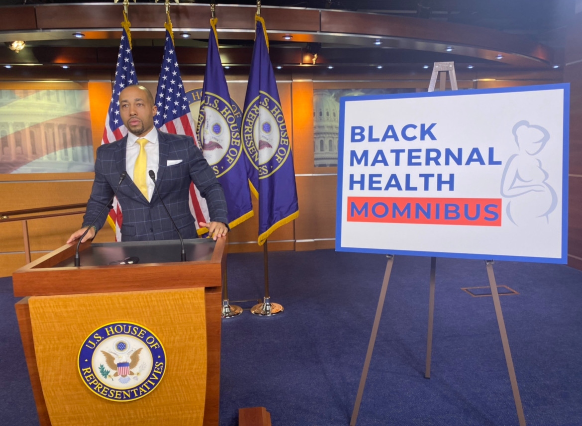 Charles Johnson at U.S. House of Representatives podium beside Black Maternal Health Momnibus sign with American flags